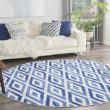 Living room scene with a white sofa and a round Nourison Whimsicle Ivory Blue rug with a geometric diamond pattern.