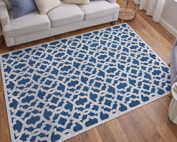 Living room scene with a Feizy Saphir Mira rug. The blue and white geometric rug sits under a white sofa on wood floors. Roomscene-Rectangle