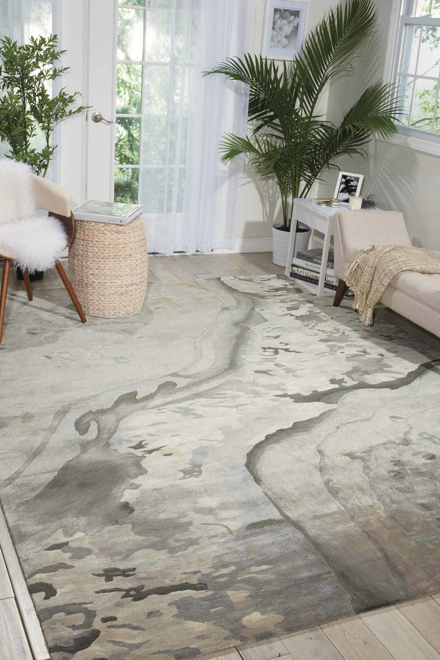 Living room scene with a Nourison Prismatic Silver Cloud rug, light wood floors, neutral sofa, and plants near a sunny window.