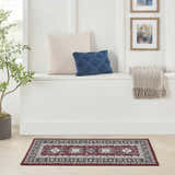 Bright entryway with a Nourison Fulton Red Vintage rug, white bench, pillows, and framed art.