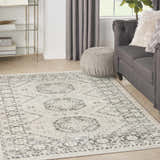Living room scene with grey sofa and Nourison Serenity Home Ivory Grey Vintage rug on wood floor.