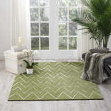 Sunlit room with a Nourison Vita Kiwi rug, light green with a white chevron pattern, paired with a plant and bench.
