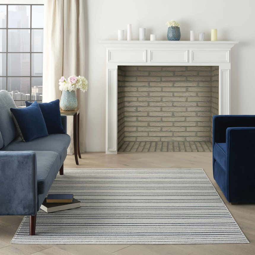 Living room with blue velvet furniture and Nourison Key Largo Blue Contemporary Area Rug on light wood floors.