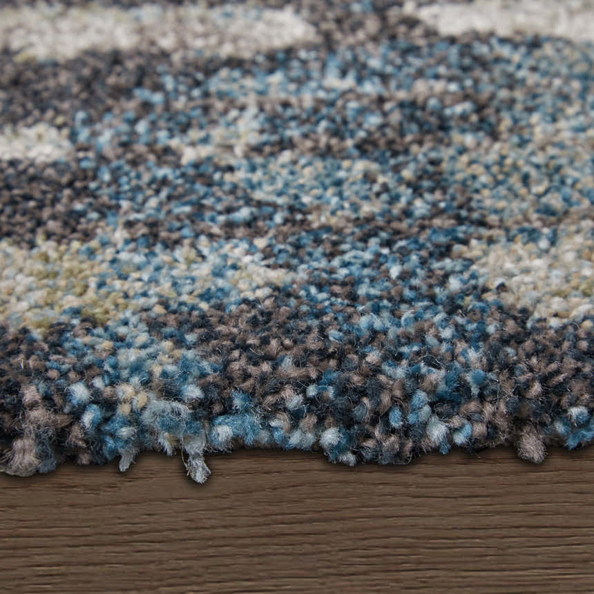 Close up of Feizy Skyview rug shows abstract gray, black, ivory and blue pattern and soft, textured pile. Pile