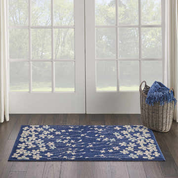Bright entryway with a Nourison Tranquil Navy rug, floral pattern, dark wood floors, and a basket with a blue throw.