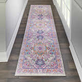 Hallway with Nourison Passion Light Grey Pink Bohemian runner rug on dark wood floor. White walls and door.