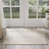 Entryway with Nourison OCEAN Pearl rug, white french doors, wood floor, and green garden view.