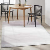 Dining room with a Calvin Klein Launder Ivory rug under a wood table and black chairs.