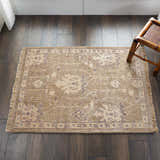 Close-up of the Nourison Aldora Opal Grey Vintage Area Rug on dark wood floors with a light floral pattern and fringe.