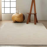 Minimalist room scene with Calvin Klein Halo Grey rug, wood side table, and modern chair by window.