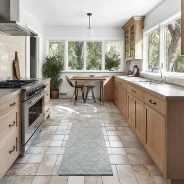 Light blue Nourison Wool Haven rug in a bright, modern kitchen with wood cabinets and table near a window.