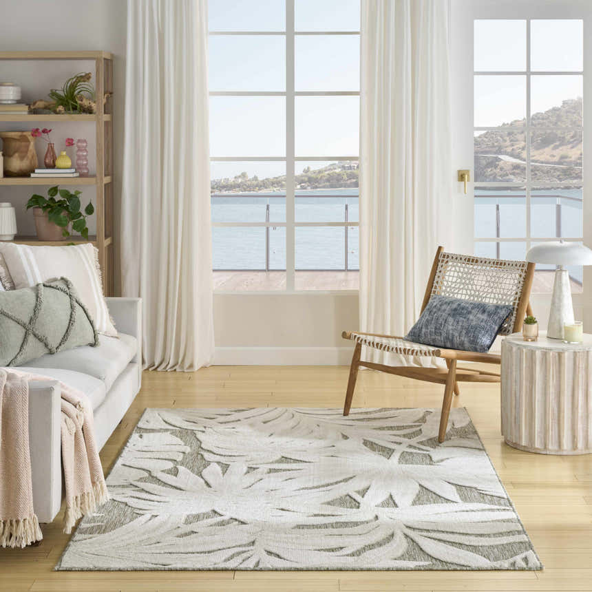 Coastal living room with Nourison Aloha Ivory Sage rug, sofa, chair, and ocean view.