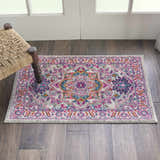 Entryway with Nourison Passion Light Grey Pink Bohemian Indoor Area Rug, wood floors, and woven chair.