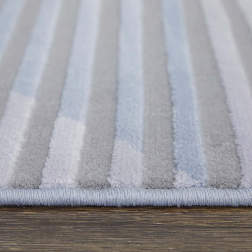 Close-up of Feizy Marigold rug. Modern geometric design in blue, gray, and white stripes. Soft, textured pile. Pile