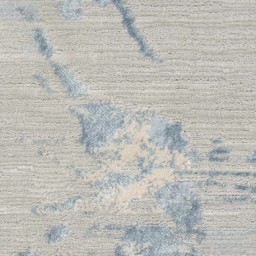 Close-up of Calvin Klein CK005 Enchanting Grey Sky rug. High pile, contemporary style with blue and cream abstract pattern.