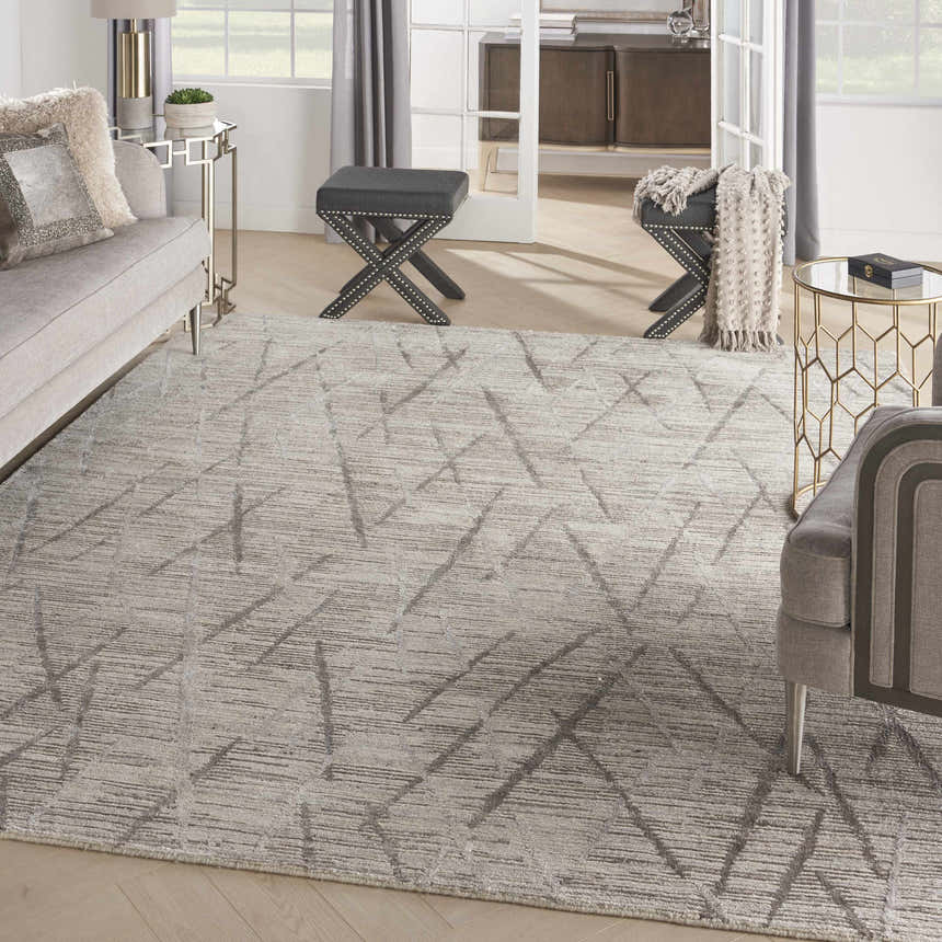 Living room scene with the Nourison OCEAN Stone rug, gray sofa, and modern gold accent tables.