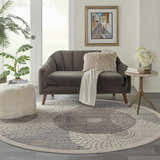 Living room scene with a grey sofa and round Nourison Graphic Illusions Grey Mid-Century Modern Area Rug.