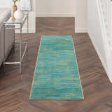 Hallway scene with Nourison Essentials Blue Green Outdoor Area Rug on herringbone wood floor.