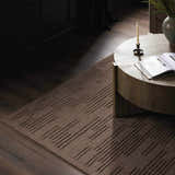 Living room scene with taupe Four Hands Geist Rug, wood floors, and round coffee table with book. Styleshot