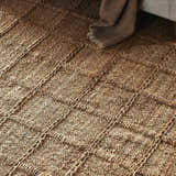 Close-up of the Four Hands Grid Jute Rug, a hand-woven natural fiber rug with a textured grid pattern. Styleshot