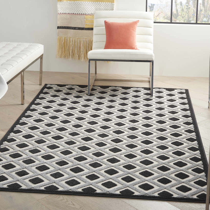 Modern living room with white furniture and Nourison Aloha Black White Area Rug featuring a geometric diamond pattern.