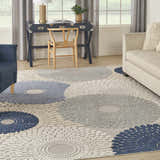 Living room scene with a Nourison Aloha Blue Grey rug, blue armchair, beige sofa, and navy desk.