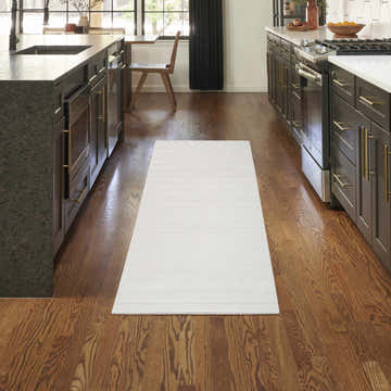 Modern kitchen with dark wood cabinets and a Nourison Essentials Ivory Grey runner rug on hardwood floors.