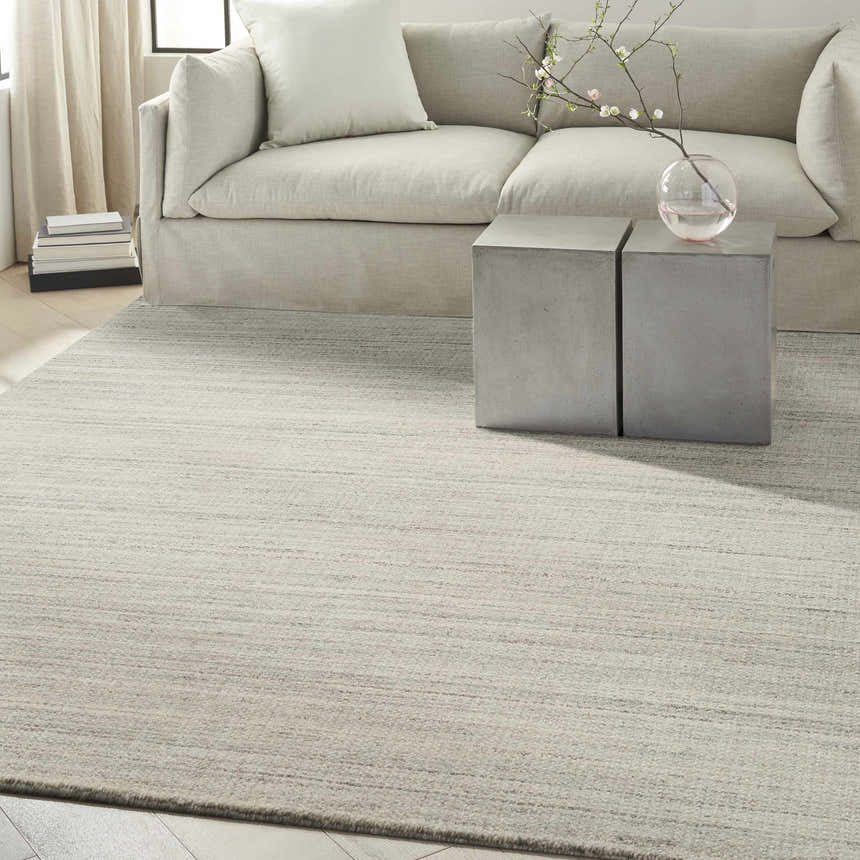 Modern living room with a Calvin Klein CK040 Abrash Grey rug, neutral sofa, and concrete side tables.