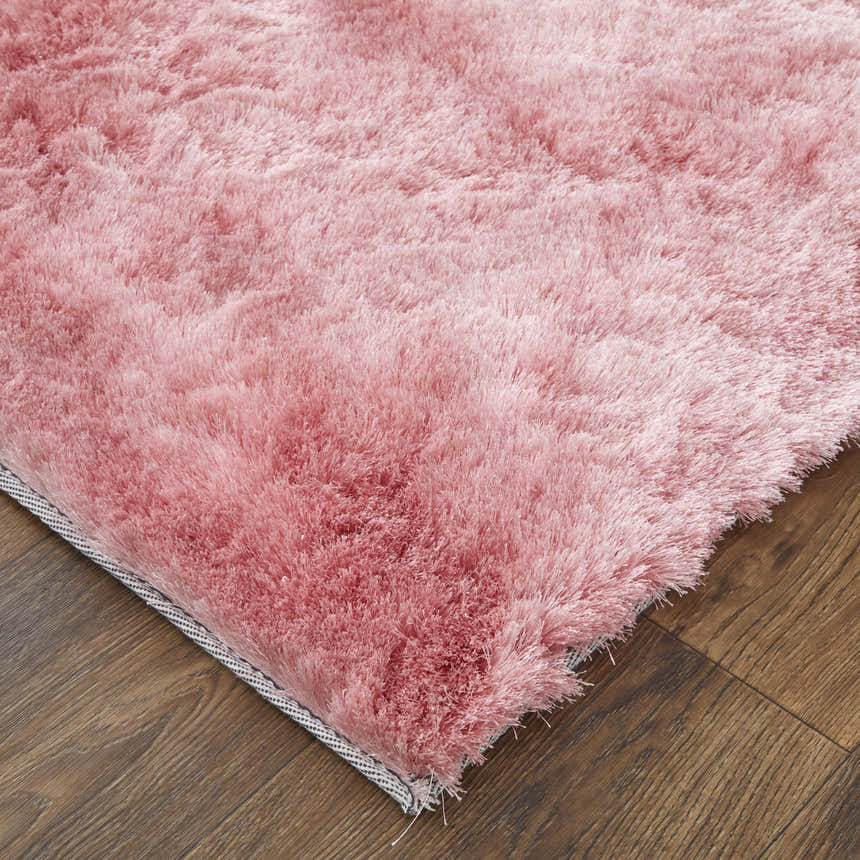 Close-up of the plush, textured Feizy Indochine blush pink area rug on a wood floor, showing its soft, shag-like pile. Corner