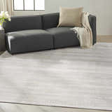 Living room scene with gray sofa and silver Calvin Klein Valley rug on light wood floor.