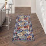 Hallway with Nourison Grafix Multicolor Bohemian runner rug on wood floor. Console table and gray sofa.
