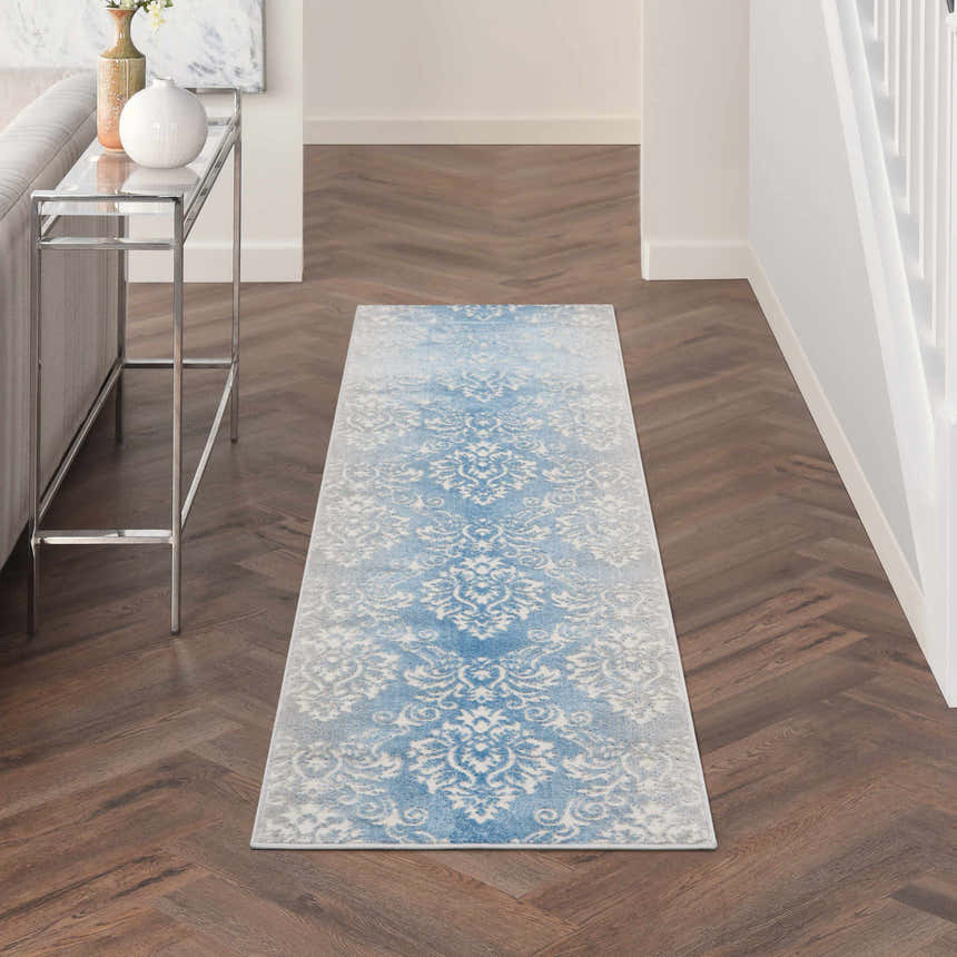 Hallway scene with Nourison Elation Ivory Blue Vintage runner rug on dark wood floor, next to a silver console table.