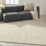 Living room scene with a gray sofa and Calvin Klein CK041 Architectura rug in natural tones and a subtle brick red grid pattern.