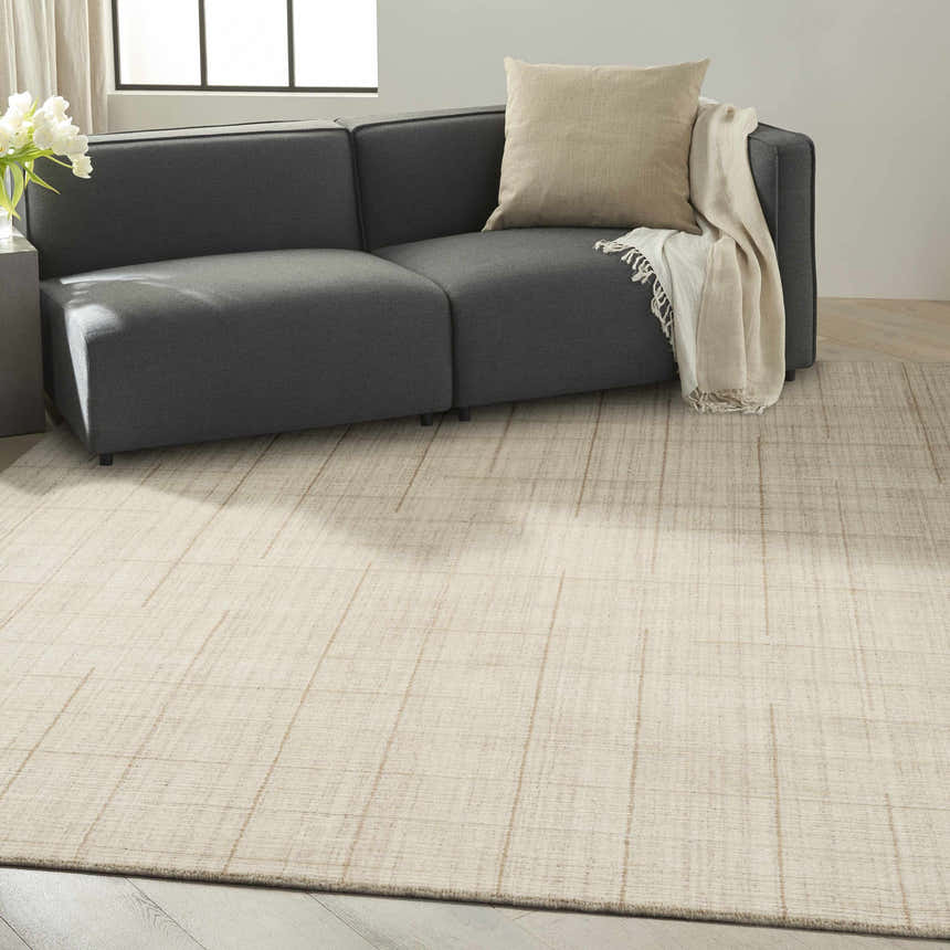Living room scene with a gray sofa and Calvin Klein CK041 Architectura rug in natural tones and a subtle brick red grid pattern.