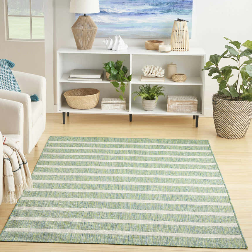 Living room scene with Nourison Positano Blue Green Ivory Modern Area Rug, white armchair, and coastal decor.