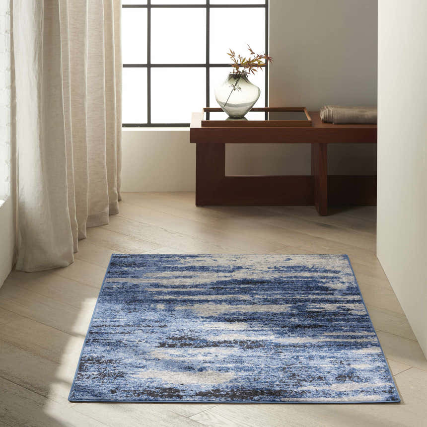 Modern room scene with a Calvin Klein River Flow Blue Grey rug, wood floors, and neutral decor.
