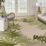 Living room with a Nourison Aloha Ivory Green Outdoor Area Rug, wicker chair, and neutral sofa.