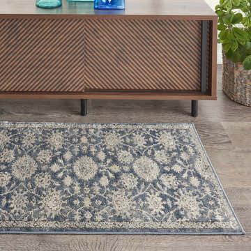 Living room scene with a blue beige Nourison Quarry vintage rug, wood console table, and potted plant.