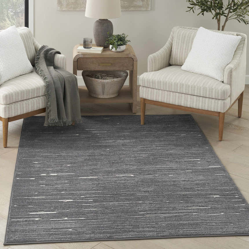 Living room scene with a Nourison Care Free Grey Modern Indoor Area Rug, chairs, and a side table.