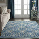 Living room with a Nourison Jubilant Ivory Blue Farmhouse Indoor Area Rug, beige sofa, and blue curtains.