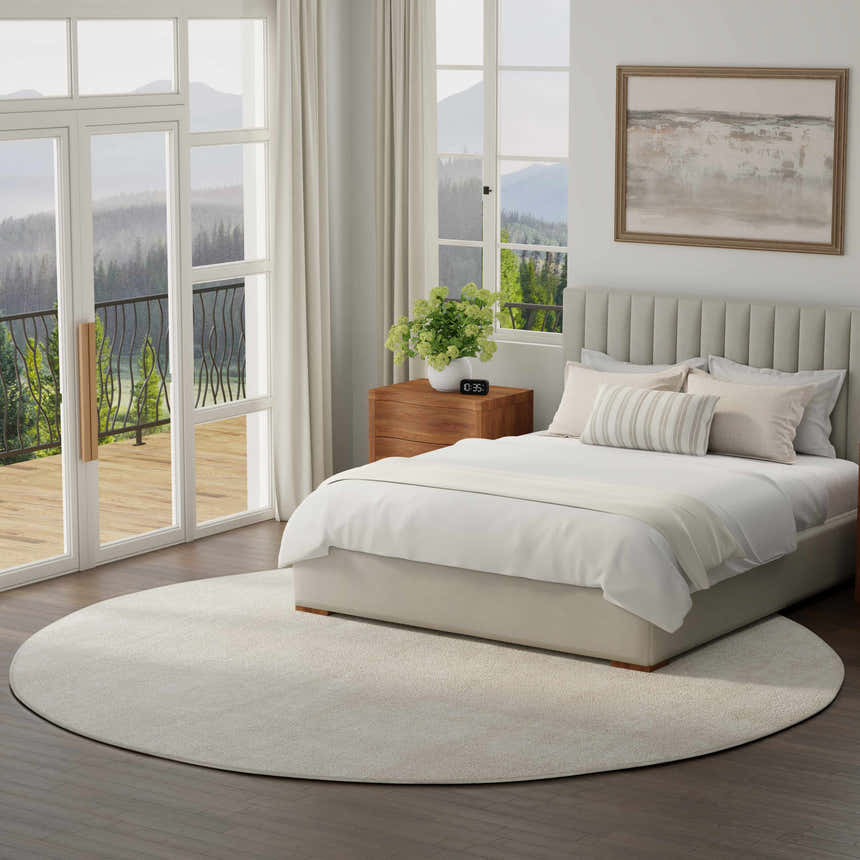 Serene bedroom with a round, ivory Nourison Serenity Home rug, wood floors, and a mountain view.