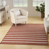 Living room scene with a Nourison Positano Terracotta Ivory rug, cream chair, light wood floors, and natural light.