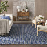 Living room scene with a Nourison Twist Reversible Blue Modern Area Rug, white sofa, wood accents, and a neutral color palette.