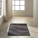 Minimalist room with a black Calvin Klein Home Prairie hair on hide area rug on light wood floors.
