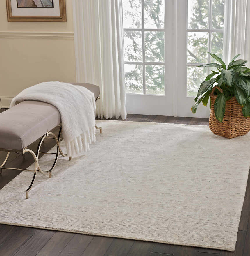 Sunlit room with Nourison OCEAN Pearl rug, bench, and plant. Neutral tones create a serene, modern space.