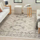 Living room with a Nourison Serenity Home Ivory Grey vintage rug, white sofa, striped ottomans, and wood accents.