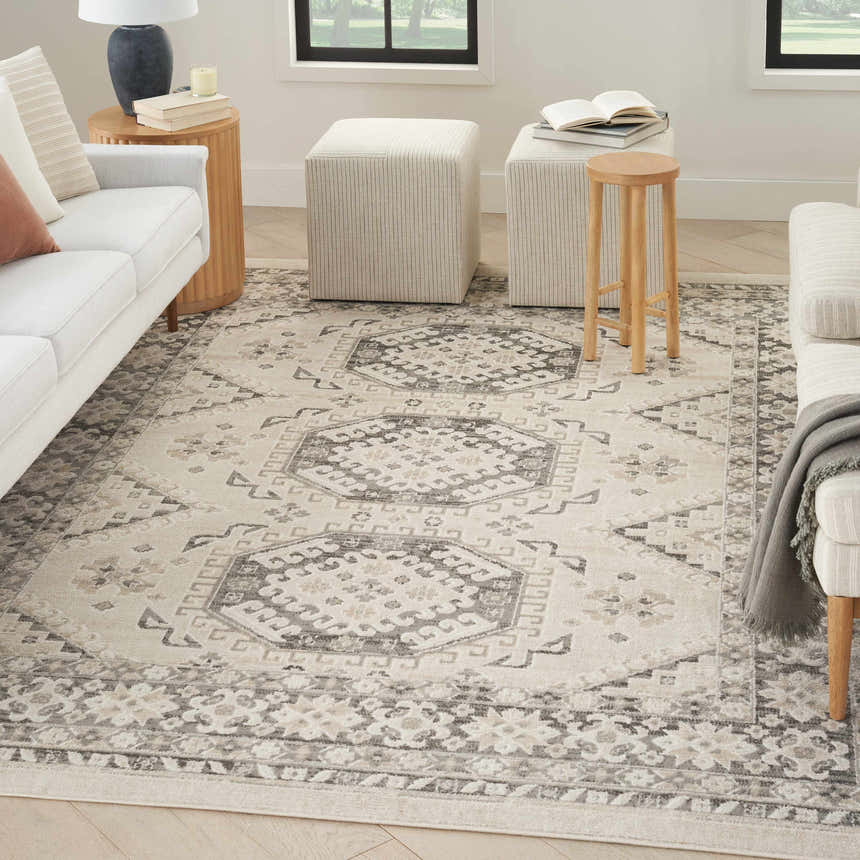 Living room with a Nourison Serenity Home Ivory Grey vintage rug, white sofa, striped ottomans, and wood accents.