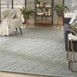 Living room scene with a Nourison Wool Haven Blue rug, gray sofa, and neutral armchair. The rug has a diamond pattern.