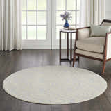 Living room scene with a round Nourison Jubilant Ivory Blue rug, chair, side table, and dark wood floors.