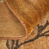 Close-up of the hand-knotted Feizy Cordonnet rug. Brown and orange wool rug with a floral and botanical pattern. Fold